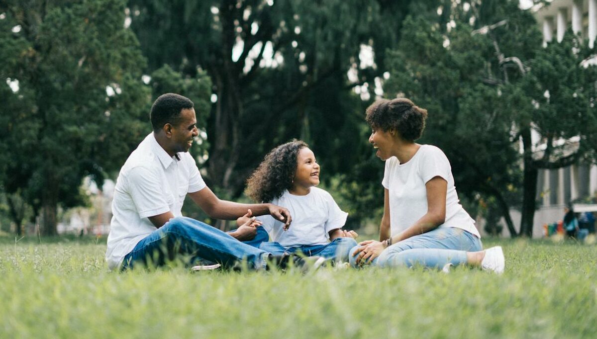 Family Sitting on Grass Near Building